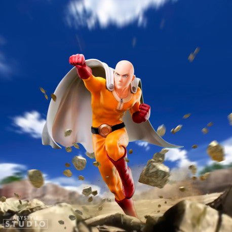 Figurine de collection Saitama One Punch Man en action, fond rochers et ciel bleu.